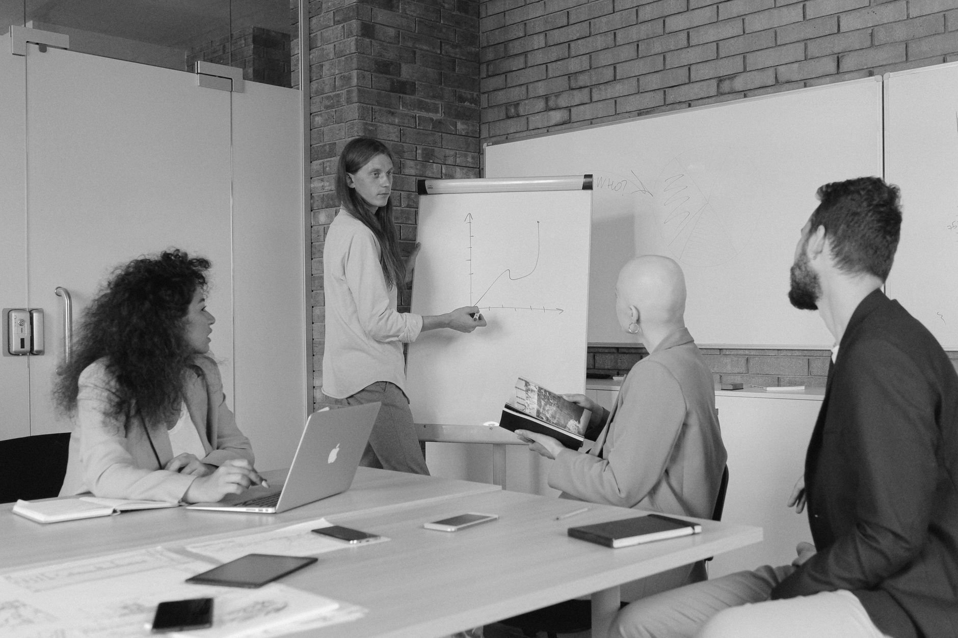 Team collaborating around a whiteboard in a brick-walled workspace