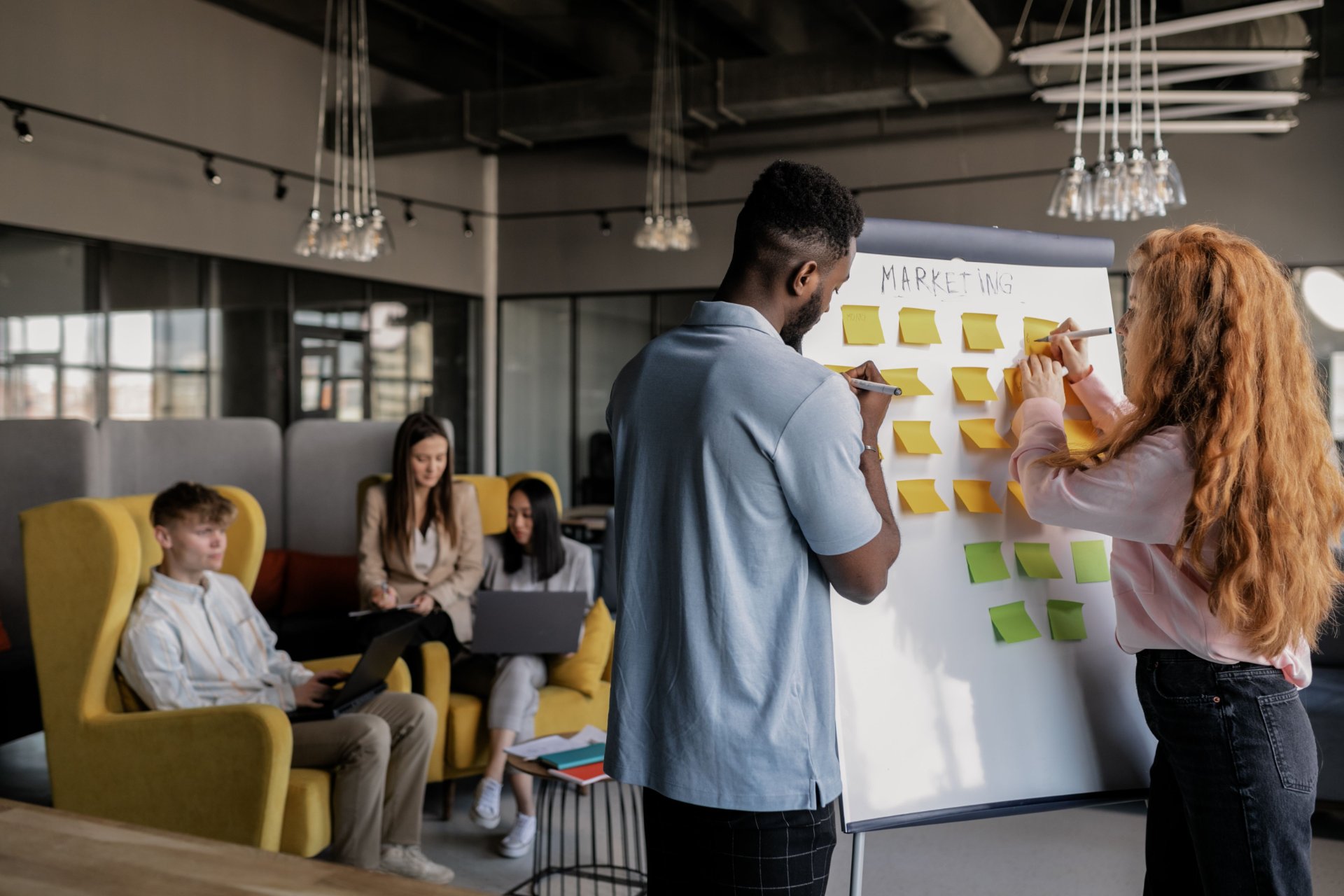 Colleagues collaborating around a sticky-note board in a bright loft office