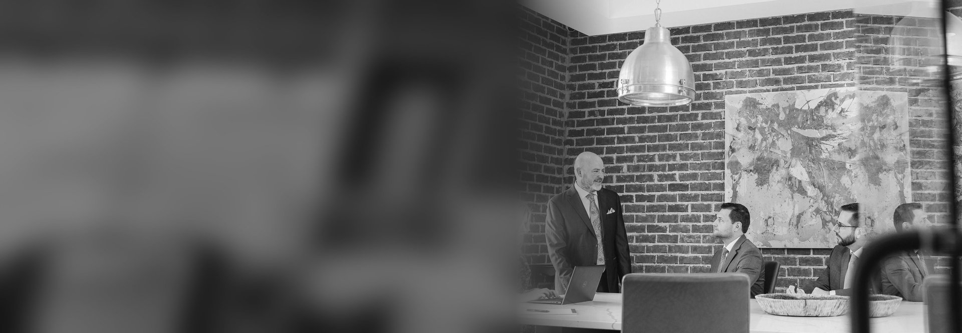 Portfolio leader standing at a conference table with his team in a brick-walled office