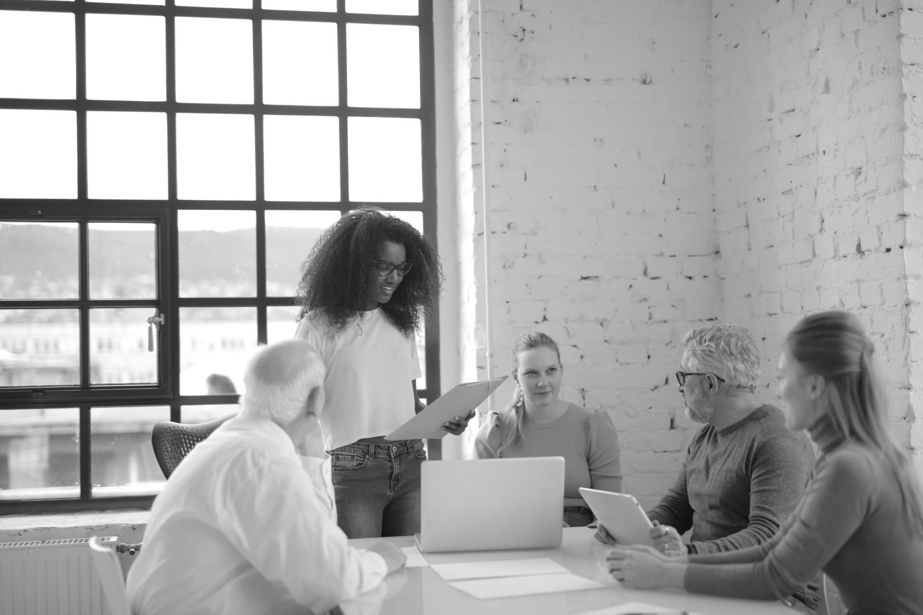 Team lead walking colleagues through a change at a table in a bright brick-walled office